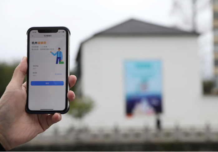 在浙江省杭州市臨安區(qū)天目山鎮(zhèn)，一名居民在“杭州健康碼”海報上掃碼申領(lǐng)個人二維碼。新華社發(fā)